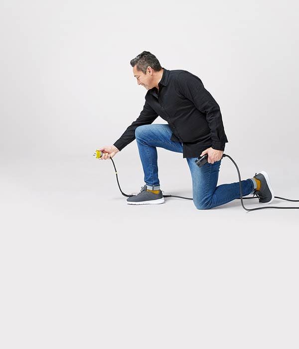 Man leaning over holding a cord with a plug.