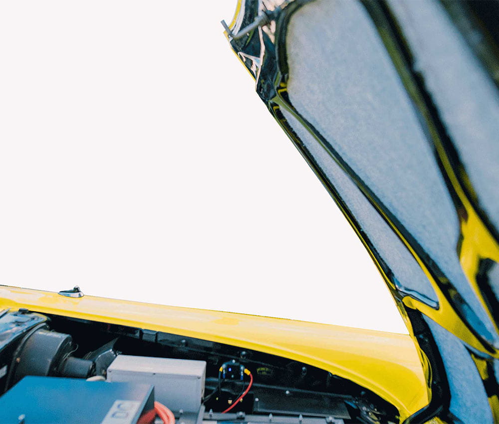 A raised hood of a Ford Fairline, showing batteries below.