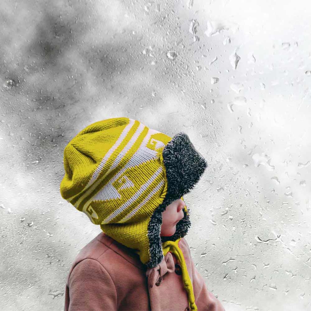 Boy with beanie and warm clothes next to a window damp with condensation
