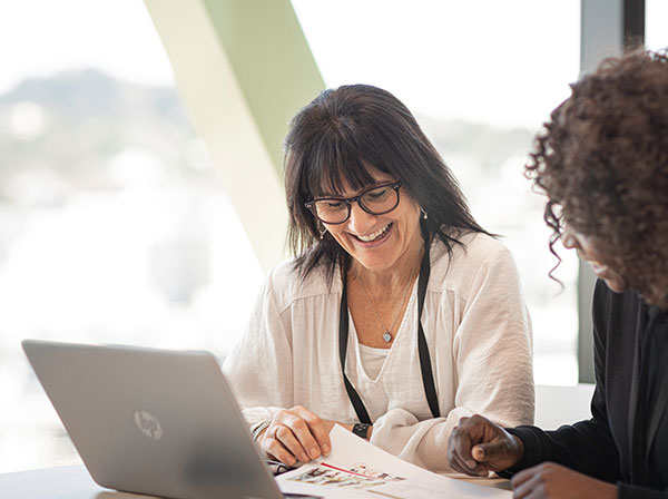 Smiling women looking over paperwork together.