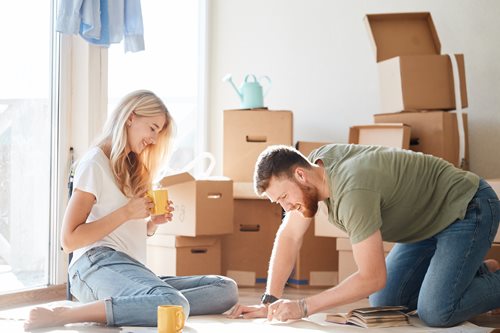 Woman and man writing a packing list while drinking a hot drink on the floor