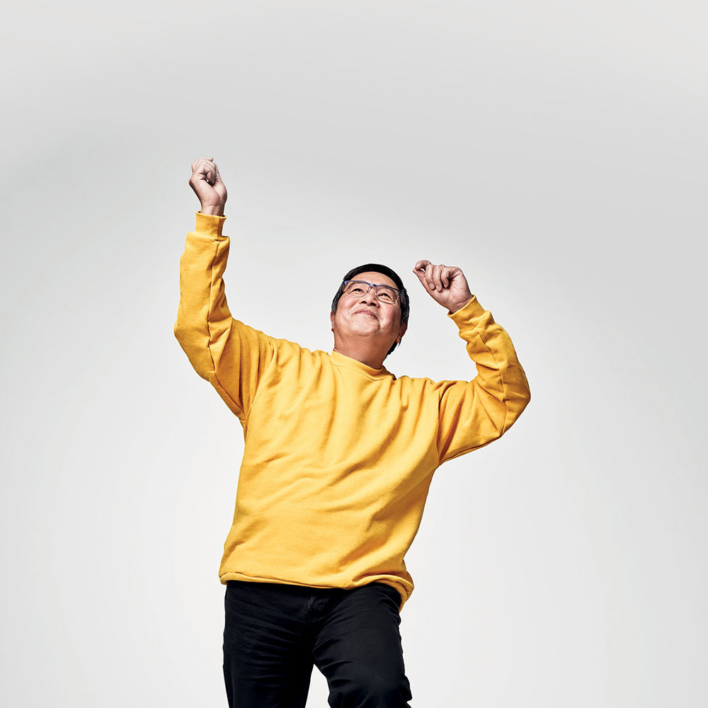 Man in yellow jumper dancing and smiling.