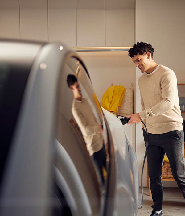 Man charging EV in garage.