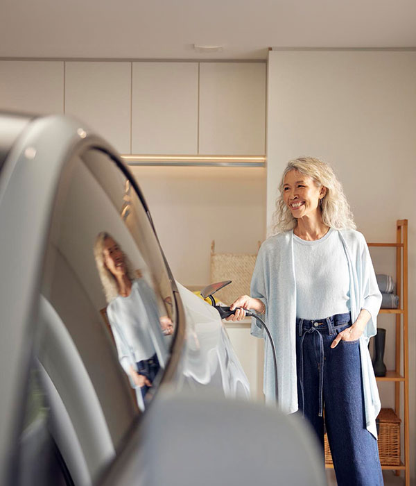 Women charging EV in garage.