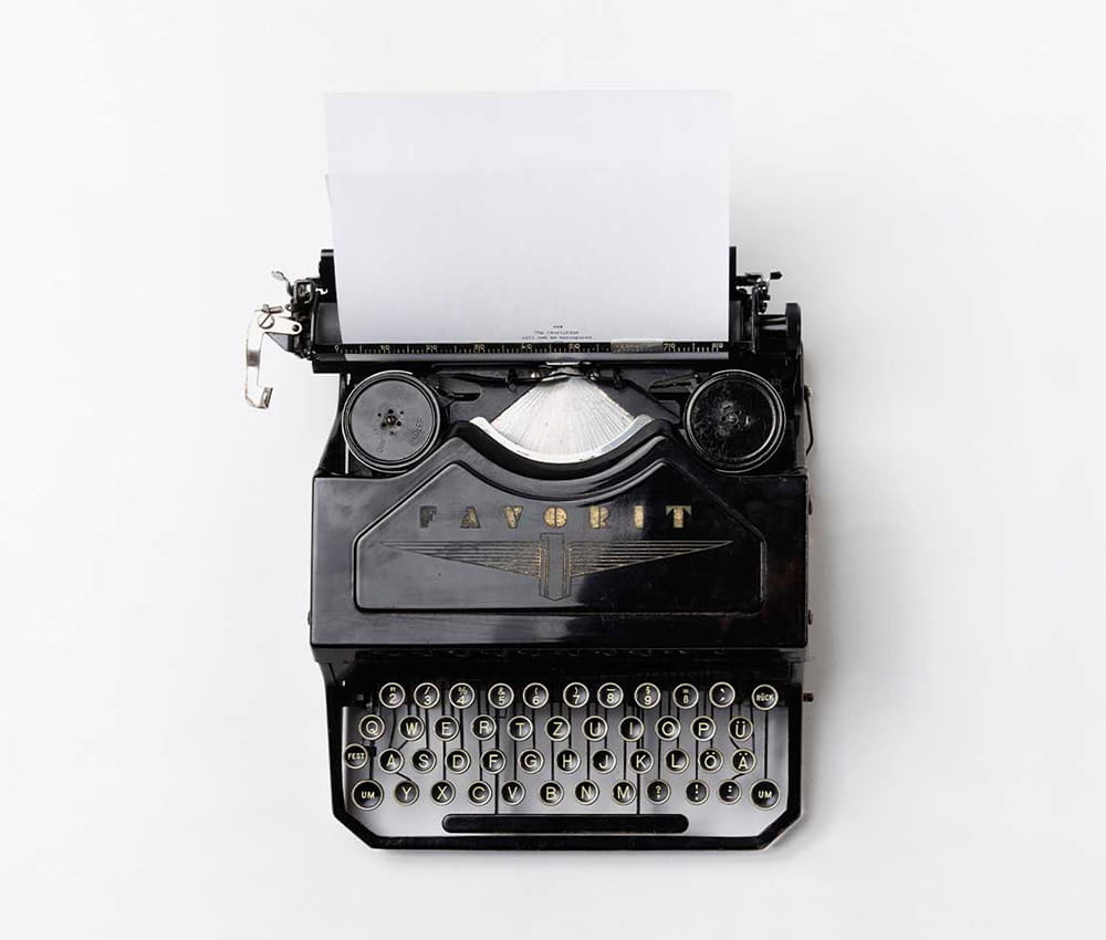 A black typewriter with white piece of paper.