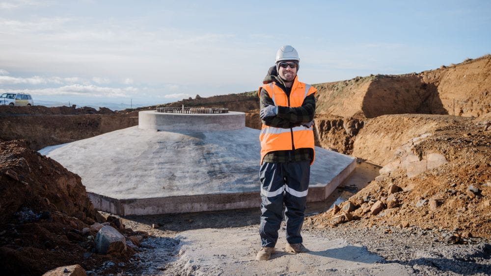 Stewart Reid stood in PPE next to the construction of a wind turbine tower base