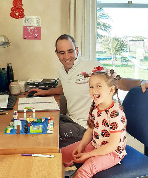 Man and daughter sitting in home office, smiling.