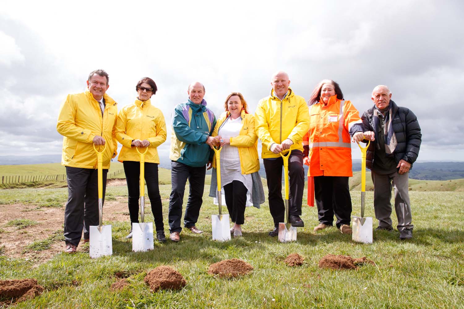 A group of people holding spades and smiling.