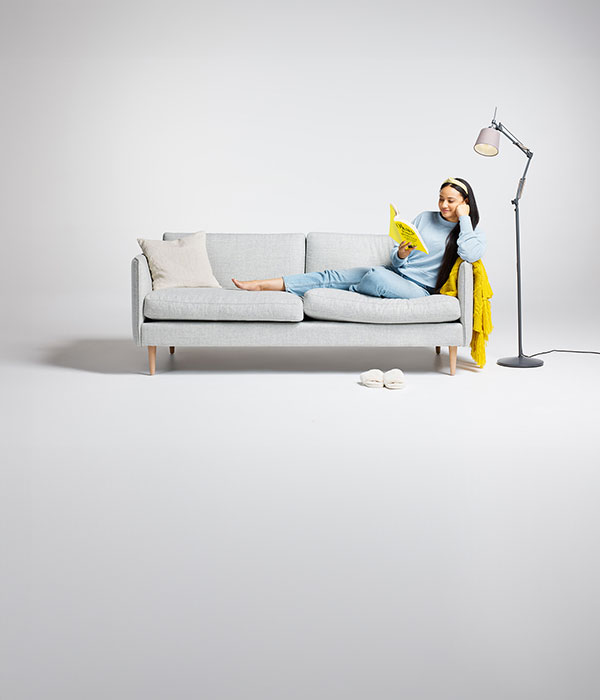 Women lounging on a couch, reading a book.