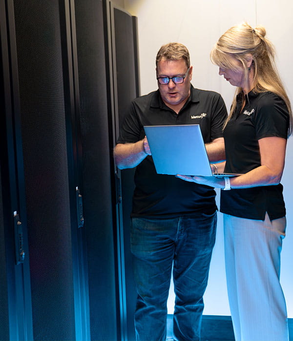 Man and a women checking laptop at data centre.