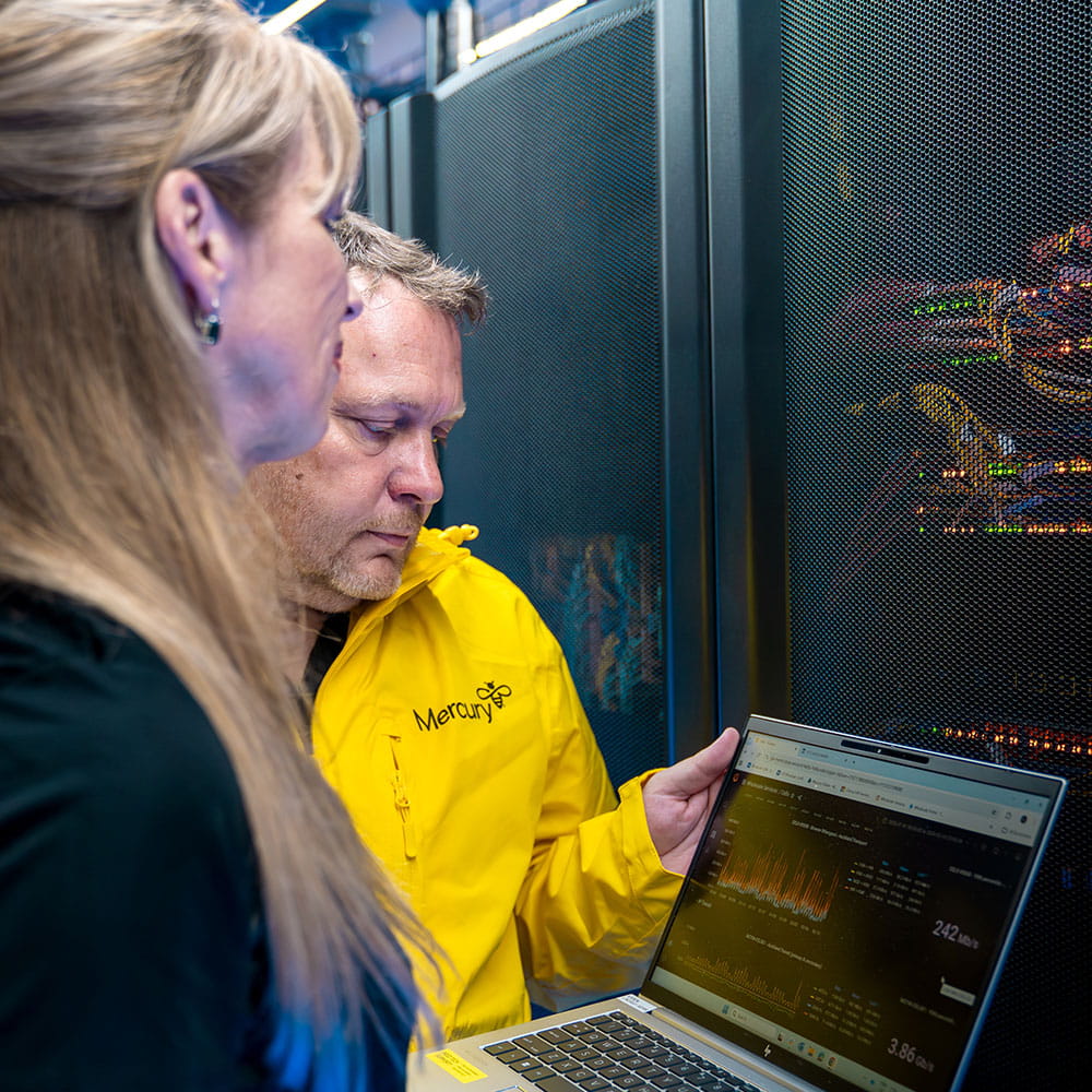Man and a women checking laptop at data centre.